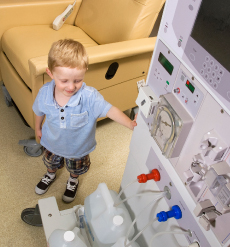 Young child standing next to a dialysis machine