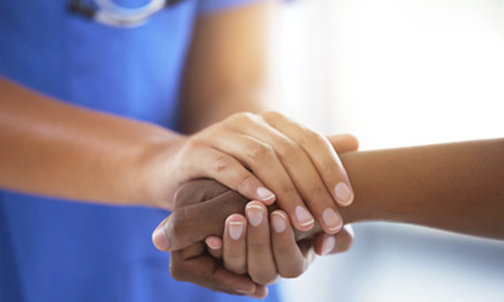 Doctors hands holding a patients' hand